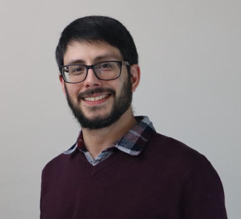 Nicholas Vanderpool, wearing glasses and a collared flannel shirt under a burgundy sweater